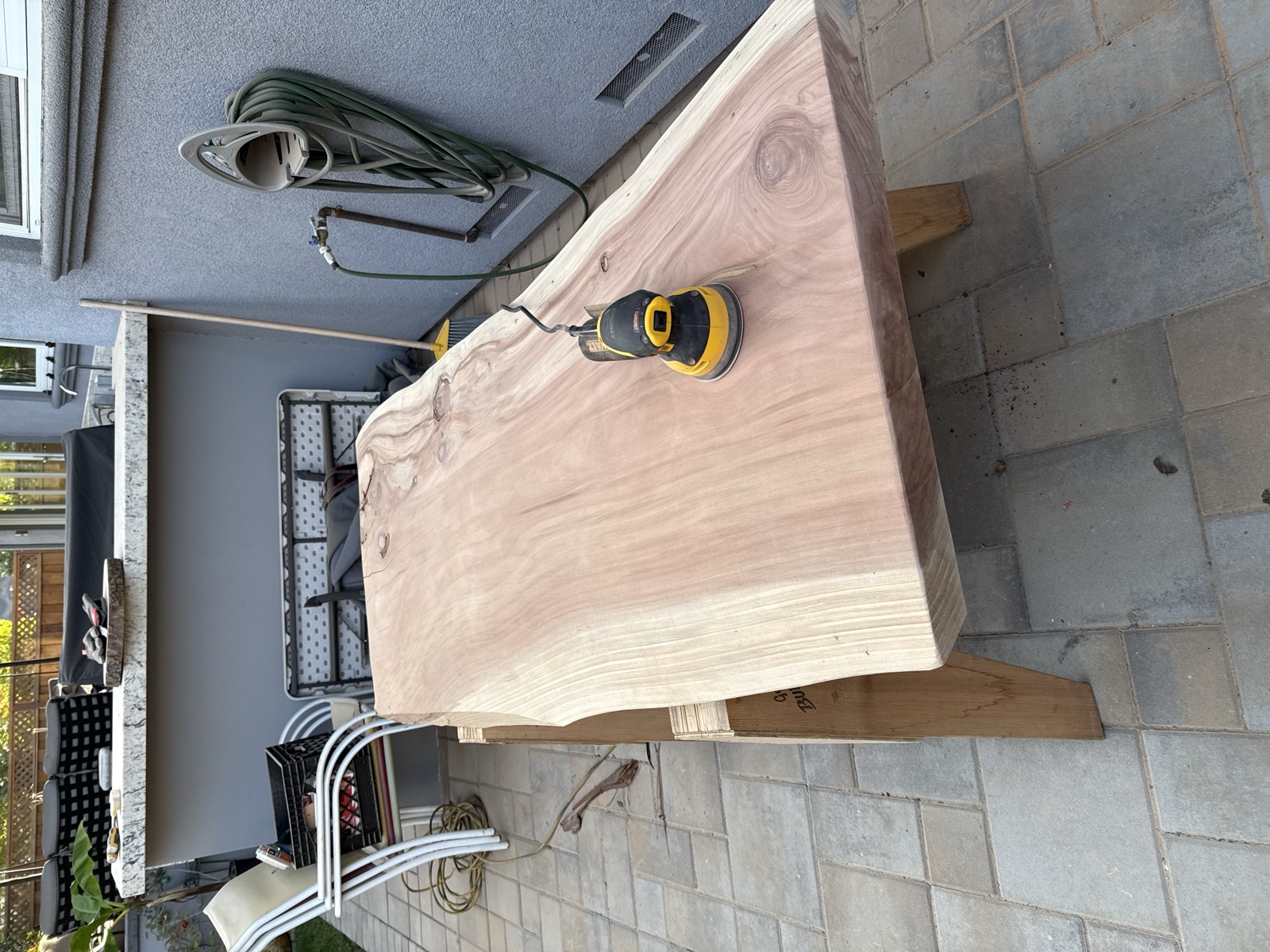 The sanded second slab on sawhorses, red heartwood down the center and a sander resting on top