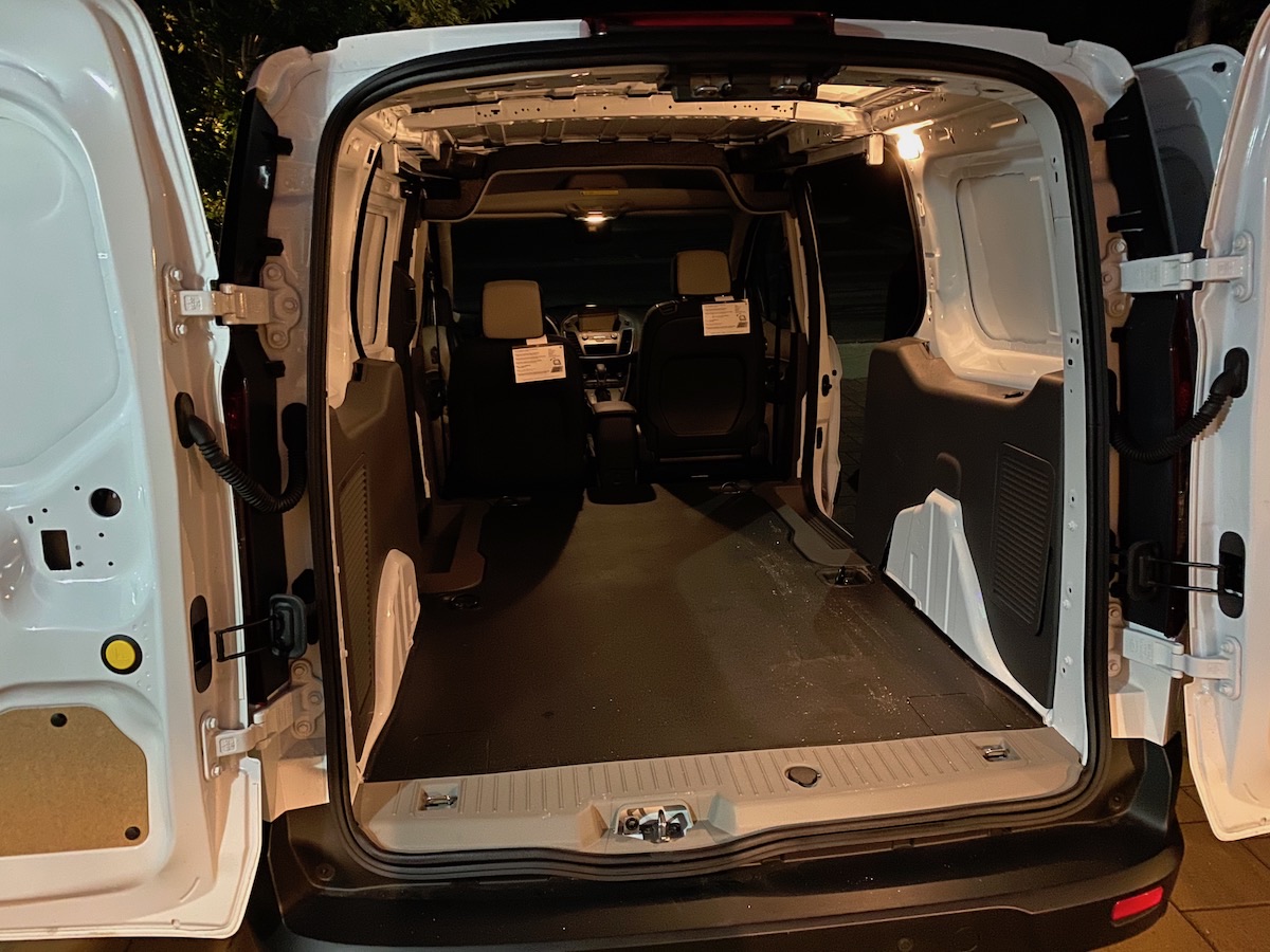The empty cargo bay of a white Ford Transit Connect with the rear doors open