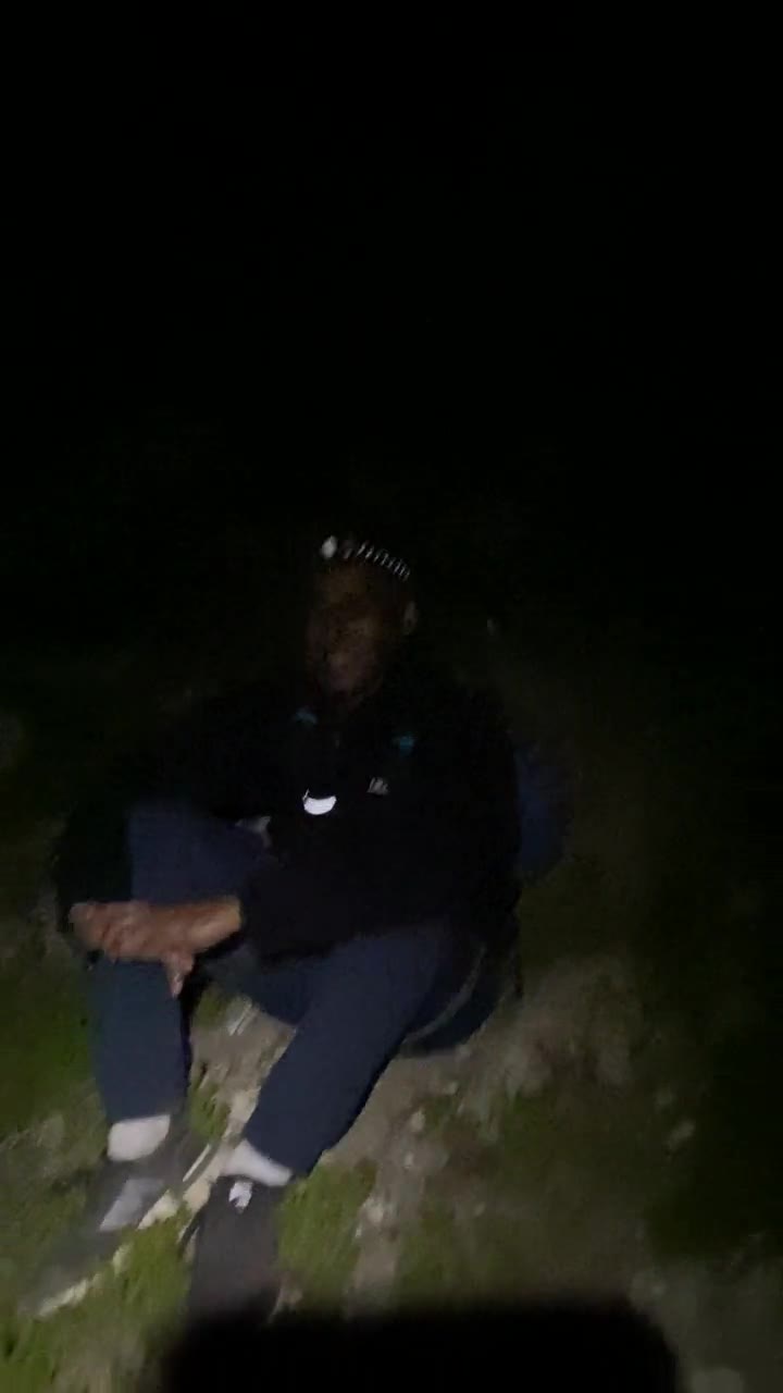 Dan sitting on the hillside at night with a headlamp