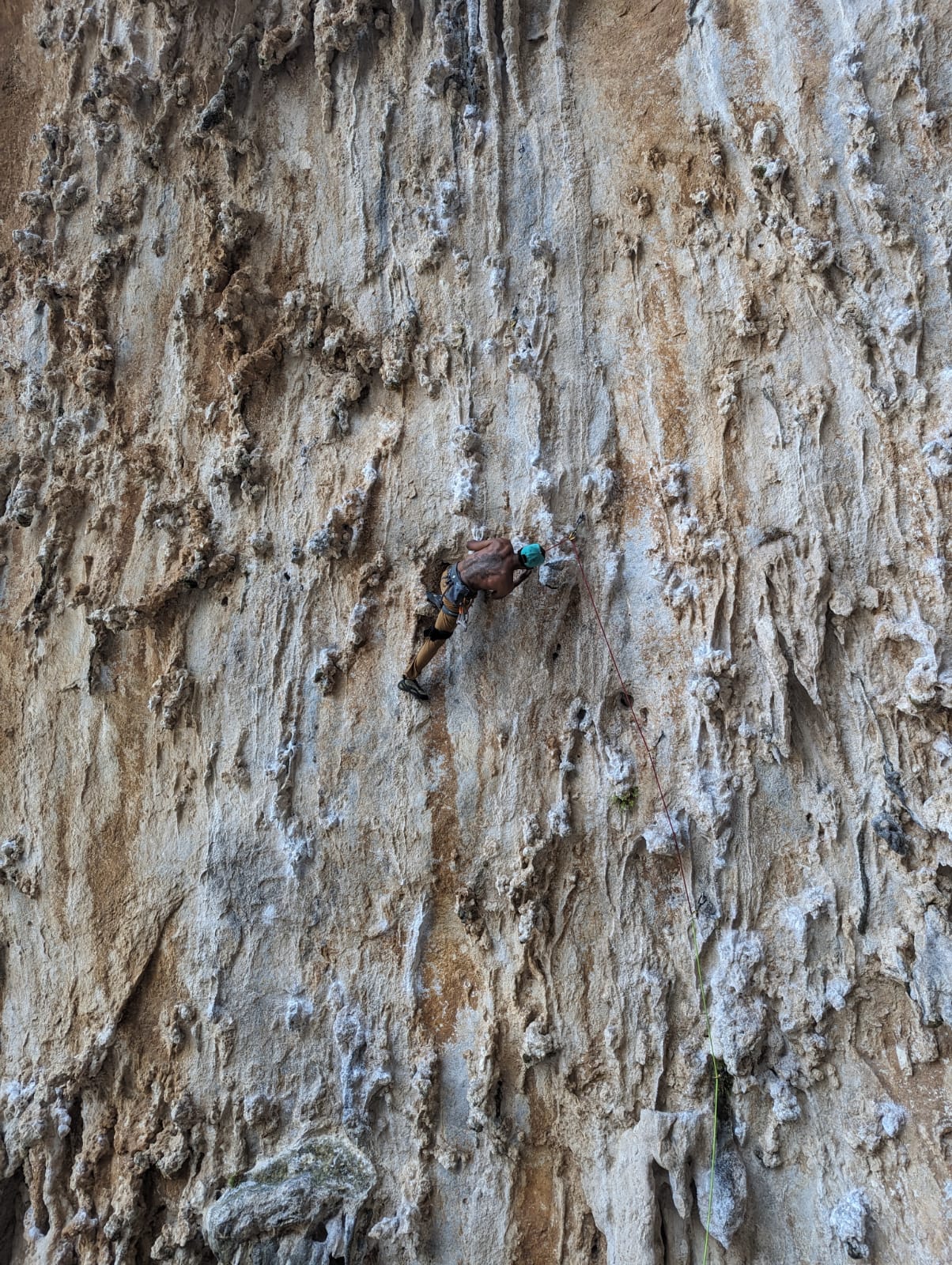 A kneebar on the tufas, helmet on, red rope clipped above