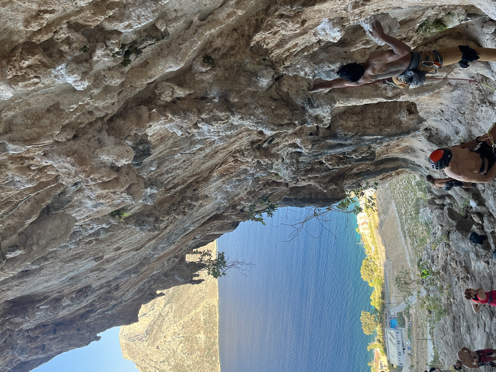 On the lower part of DNA with a knee pad on, Telendos and the sea behind the cave