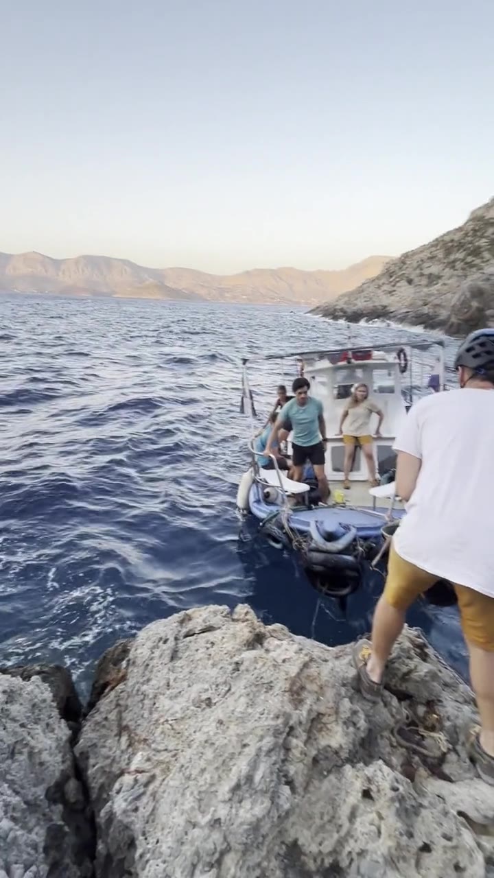 A boat coming into a rocky landing, someone in a helmet waiting on the rock