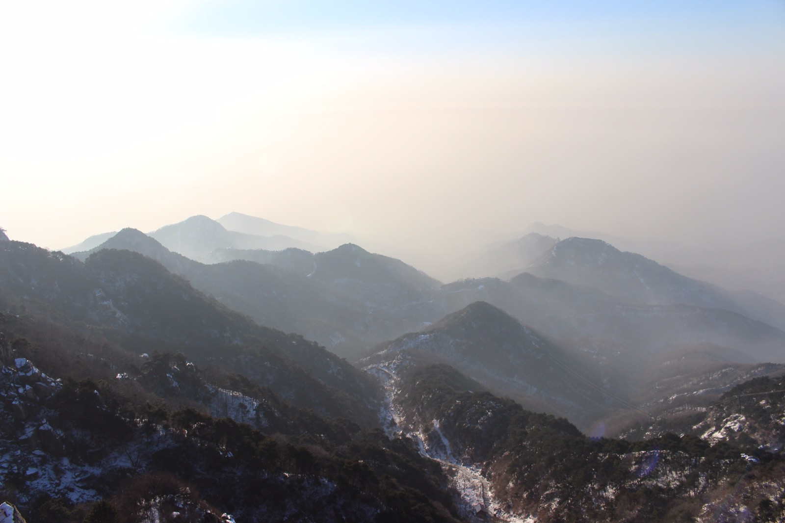 Snow-dusted ridgelines fading into haze from the top of Mount Tai