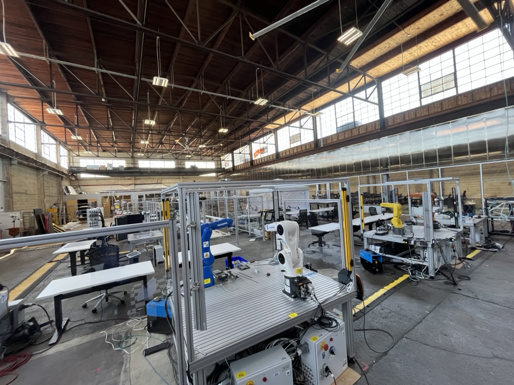 Robot work cells in aluminum extrusion enclosures on a warehouse floor