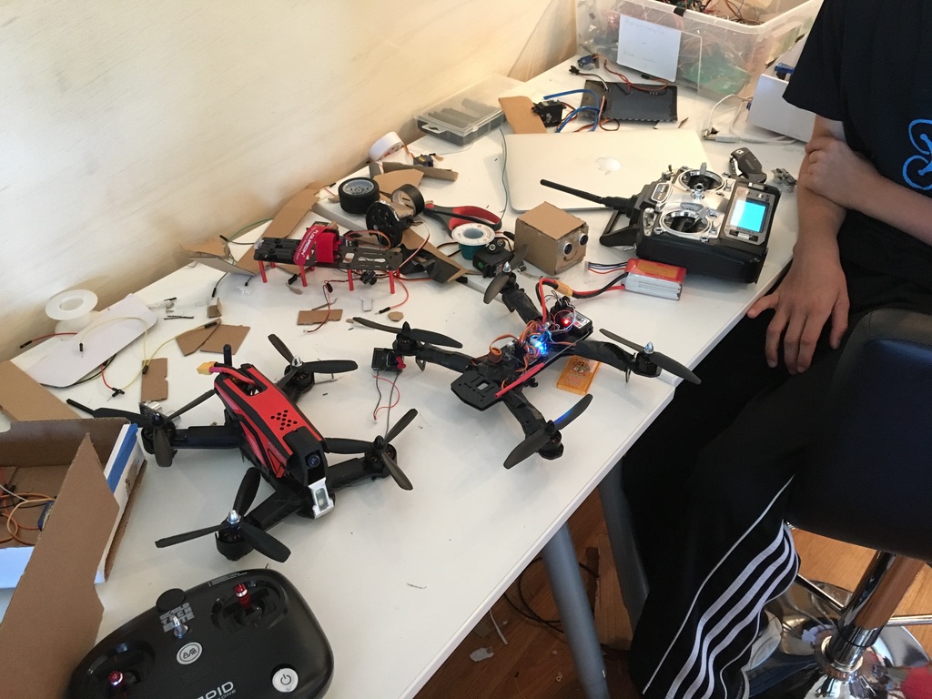 Racing drones and transmitters mid-repair on a workbench