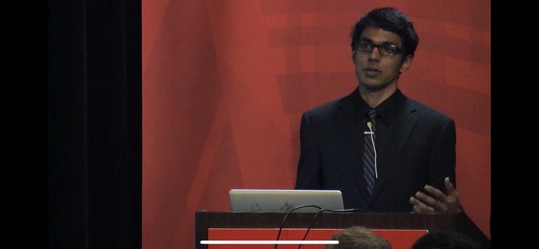 Speaking at a podium in front of a red backdrop at the Wolfram Technology Conference